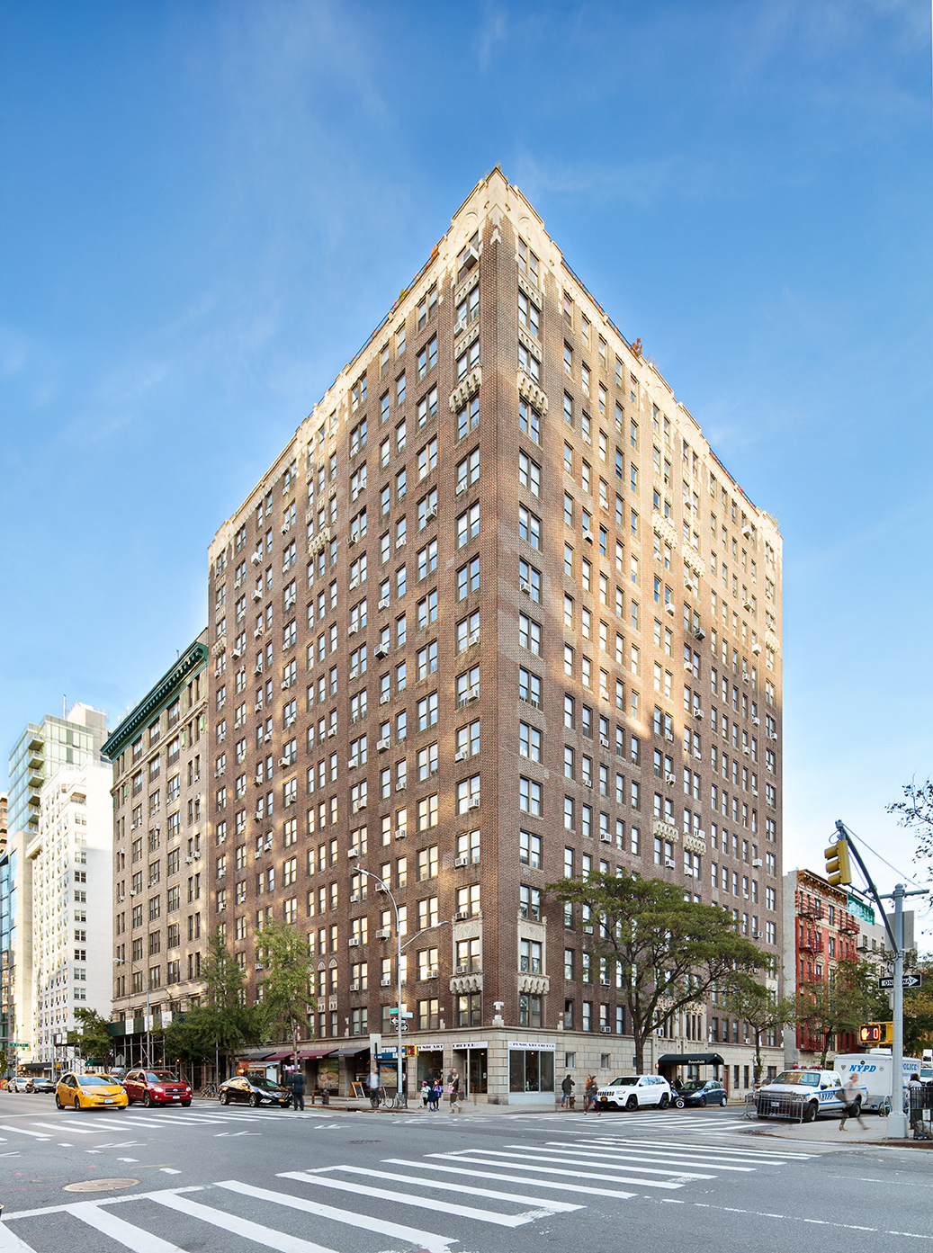 A large brown building is in the middle of a city street.